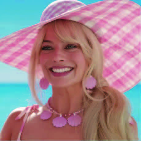 A close-up of Margot Robbie as the Original Barbie, wearing a bright smile and a large pink sunhat at the beach. Ken is nowhere in sight