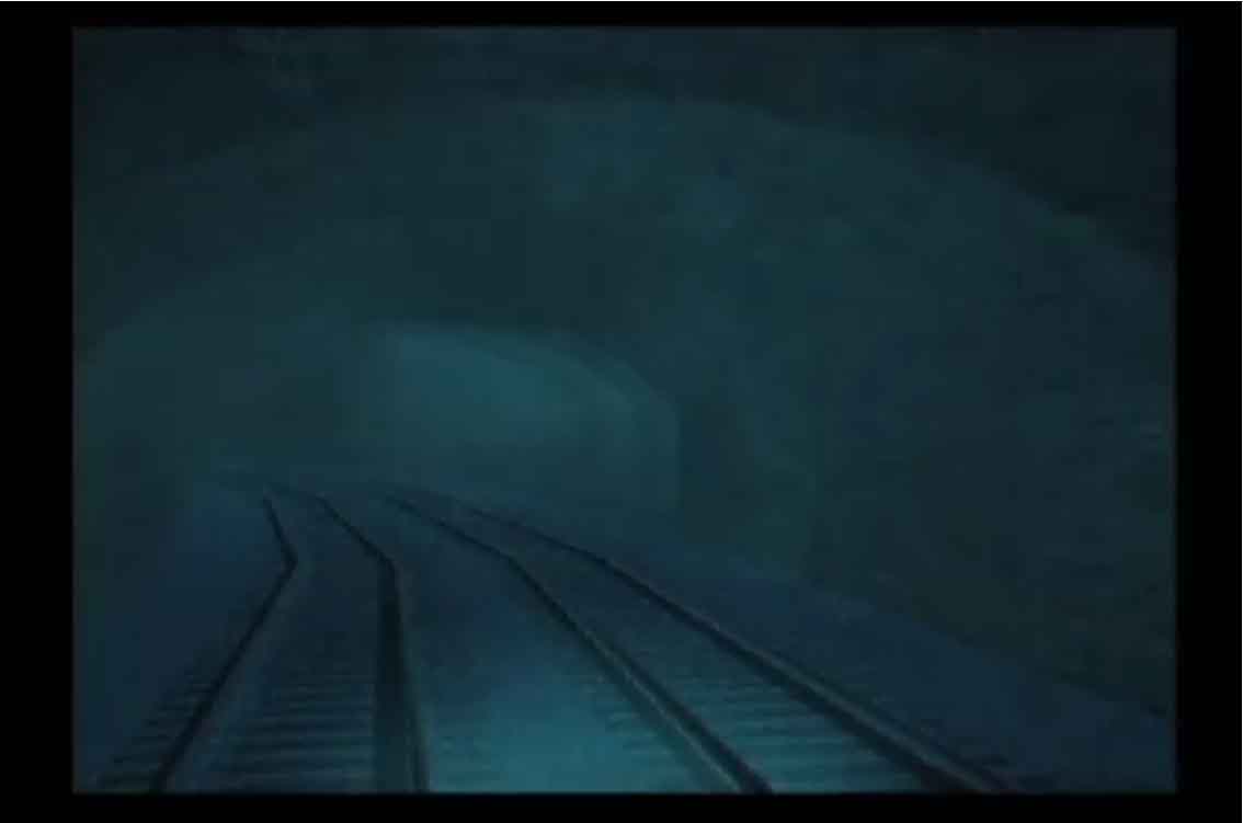 A still from Phil Solomon's Rehearsals for Retirement shows empty train tracks disappearing into a foggy tunnel. The scene is set at nighttime, casting an eerie ambiance over the mysterious and atmospheric setting.